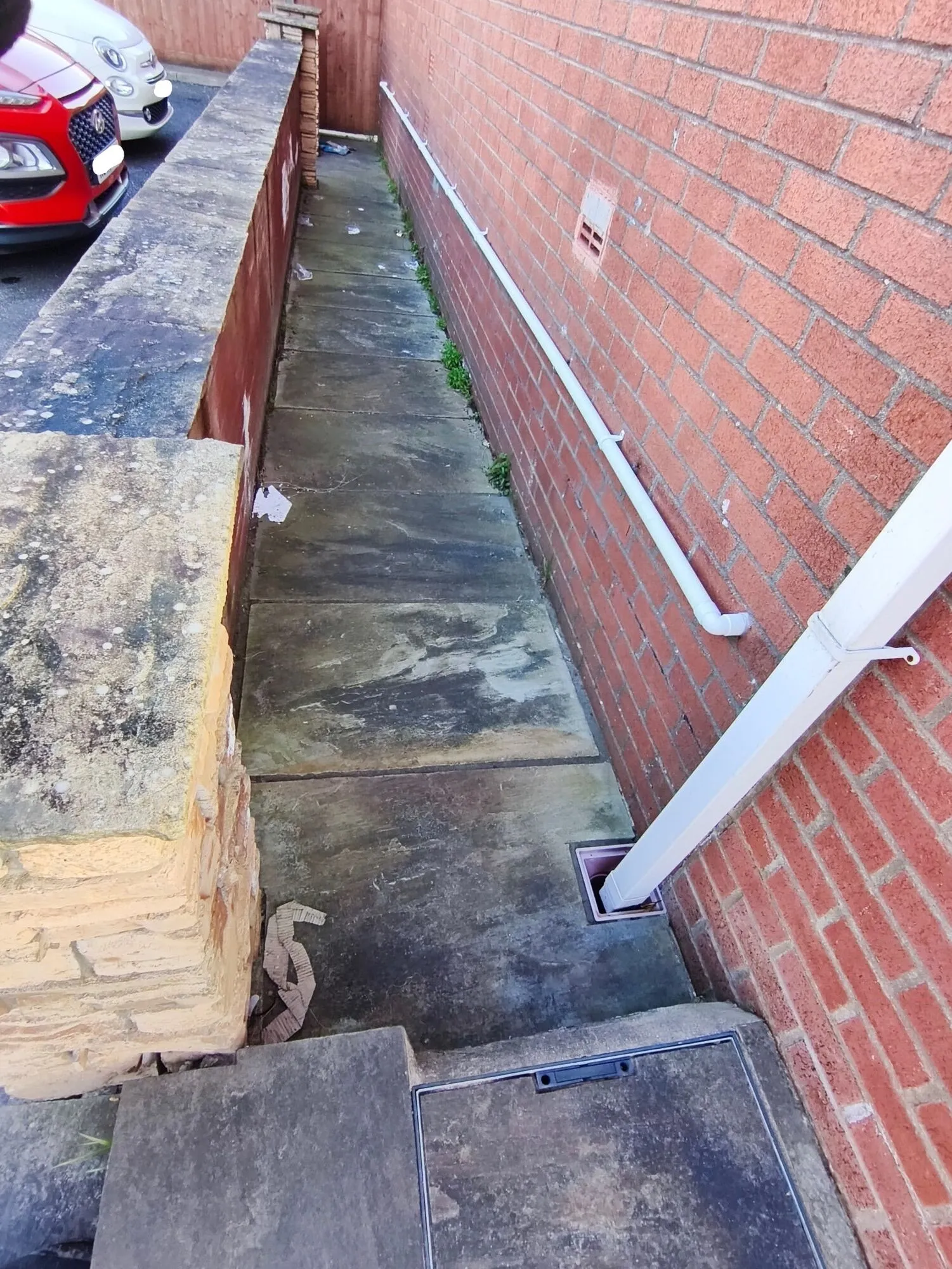 Before sidepath cleaning: weathered paving with organic growth and staining